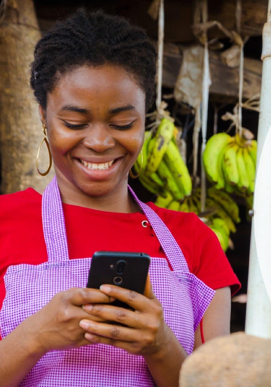Market vendor smiling as she uses a USSD menu on her phone